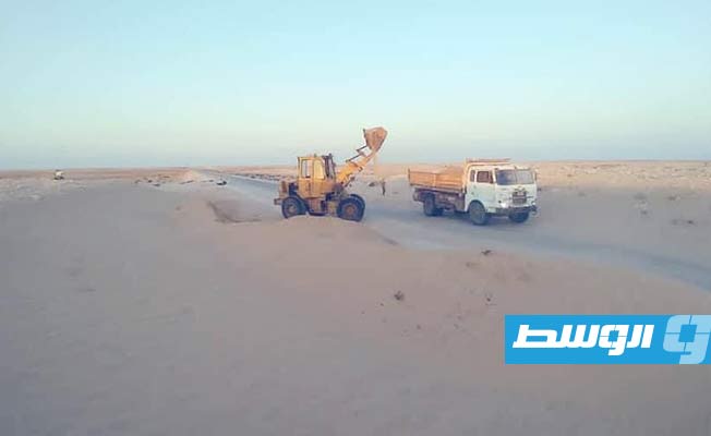 مواطن يتطوع بإزالة الرمال الزاحفة على طريق طبرق - أجدابيا