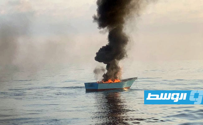 النار مشتعلة في القارب بعد إنقاذ المهاجرين ونقلهم إلى زورق حرس السواحل. (مكتب المراسم والإعلام برئاسة أركان القوات البحرية الليبية)