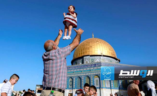 فلسطيني يلاعب طفلته في مجمع الأقصى (رويترز)