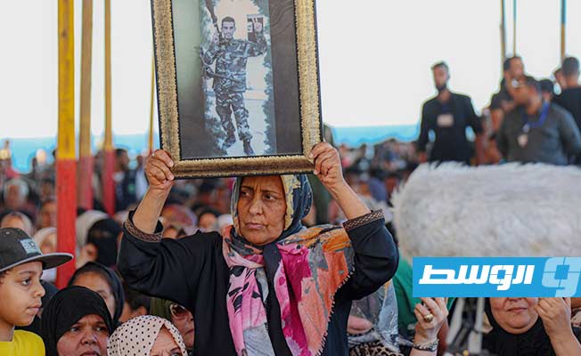 سيدة تحمل صورة أحد «شهداء الكرامة» خلال استقبال المشير حفتر في درنة.4 يوليو 2022. (مكتب إعلام القيادة).