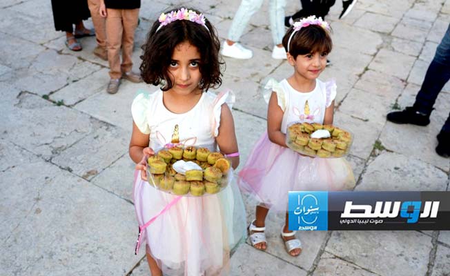 فتاتان تحملان صواني من الحلوى لتقديمها للناس بعد صلاة العيد في مجمع الأقصى بالقدس (رويترز)