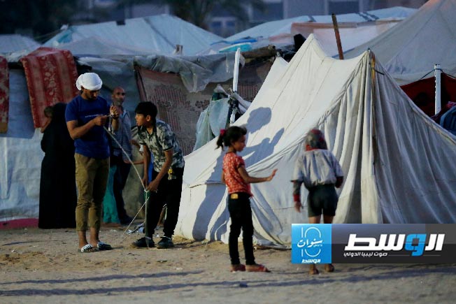 فلسطينيون حول خيمة نازحين في غزة. (الأنروا)