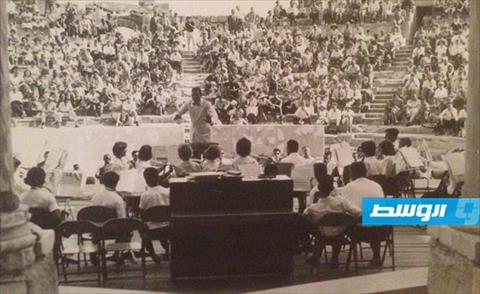 الهادي الشريف أثناء قيادته للفرقة الموسيقية لقاعدة ويليز الأميركية بمسرح صبراتـة الأثري بستينيات (فيسبوك)