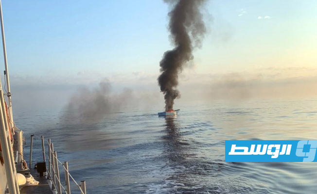 النار مشتعلة في القارب بعد انقاذ المهاجرين ونقلهم إلى زورق حرس السواحل. (مكتب المراسم والإعلام برئاسة أركان القوات البحرية الليبية)