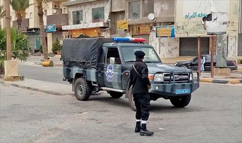 أحد العناصر الأمنية بجوار سيارة شرطة دفع بها من أمن طرابلس في ترهونة