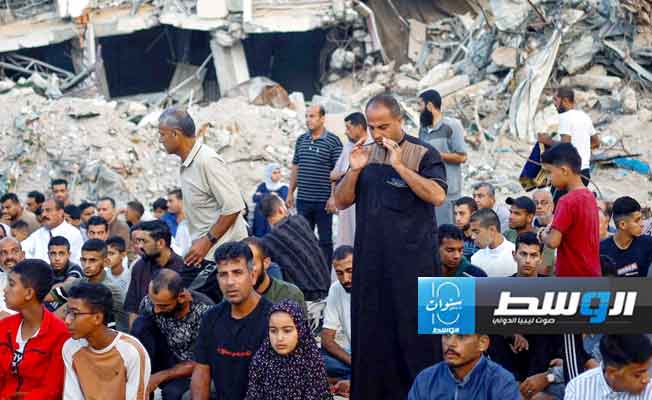 فلسطينيون يؤدون الصلاة علي أنقاض مسجد الرحمة الذي دمرته غارات جوية إسرائيلية في خان يونس بجنوب قطاع غزة (رويترز)