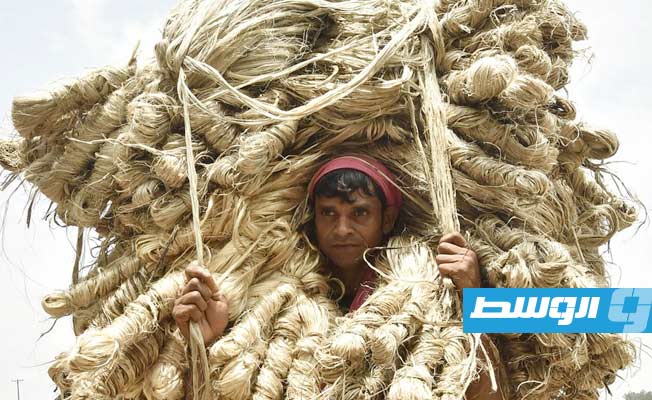 مزارع يحمل حزما من الجوت المحصود حديثا في أحد أسواق الجملة بمنطقة مانيكغانج بوسط بنغلادش، 4 أغسطس 2021. (شينخوا)