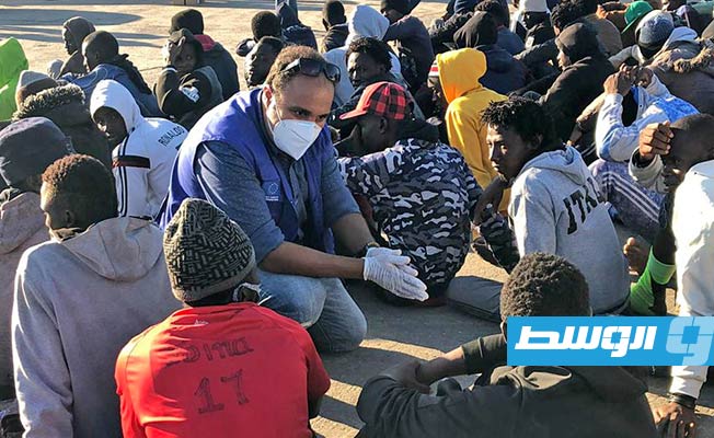 موظفان من المنظمة الدولية للهجرة خلال استقبال المهاجرين بعد إعادتهم إلى ليبيا. (المنظمة الدولية للهجرة)