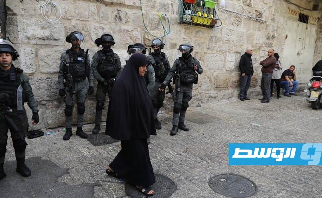 مرأة فلسطينية خلفها جنود الاحتلال قرب المسجد الأقصى, 17 إبريل 2022. (وكالة وفا الفلسطينية)