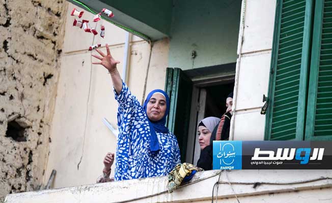 امرأة تلقي الحلوى أثناء صلاة العيد أمام مسجد السيدة زينب في القاهرة (إ.ب.أ)