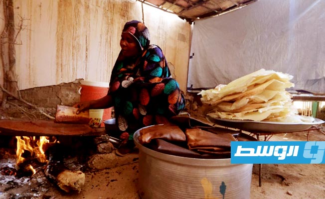 امرأة سودانية تحضّر مشروب الحلو المر المحبب في السودان خلال شهر رمضان، في قربة أم عشر جنوبي العاصمة الخرطوم في 20 مارس 2023 (أ ف ب)