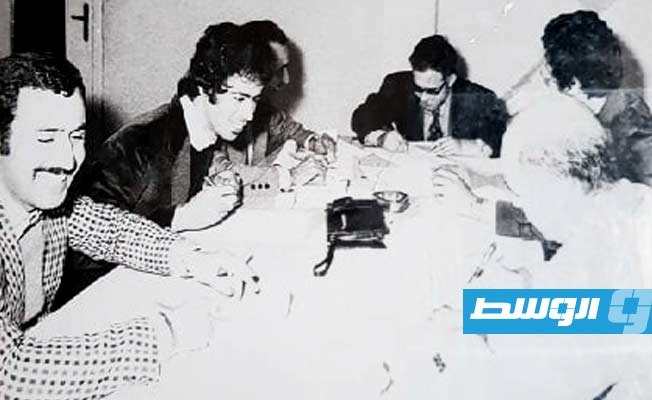 غرفة المندوبين بمقر وكالة الأنباء، طريق الشط بطرابلس، العام 1975. يتصدر الجلسة الصحفي، الدبلوماسي لاحقا، الأستاذ فرج اللموشي، ومن اليسار: أبوالقاسم عكرة، بشير زعبيه، العجيلي قعاس، ويمينا: محمد أبوساق البركي، ومحمود البوسيفي. (صفحة بشير زعبيه، فيسبوك)
