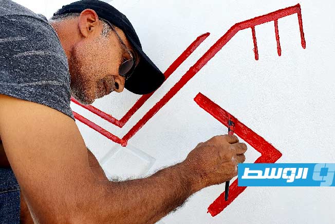 الفنان التطوعي يونس المعروق أثناء عمله في أحد مباني قرية إيند عيسى. (فيسبوك)