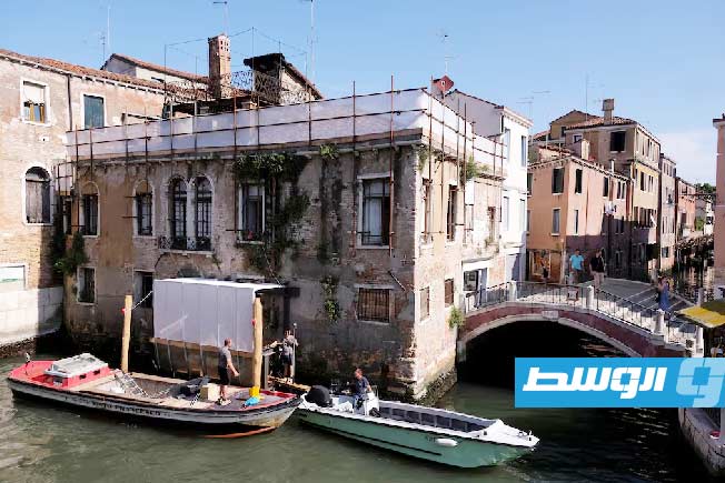 أشخاص يعملون في بداية عملية ترميم جدارية «الطفل المهاجر» لبانكسي، إيطاليا، 17 يونيو 2025. ظهرت الجدارية على قصر سان بانتالون العام 2019، وستتولى شركة «إيفيس آرت» ترميمها. (رويترز)
