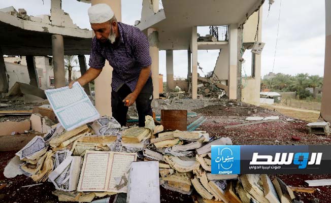 مسن فلسطيني يعاين نسخة ممزقة من المصحف الشريف ضمن آثار التدمير في أحد المساجد جراء غارة عدوانية إسرائيلية على غزة، 7 أكتوبر 2024. (وفا)