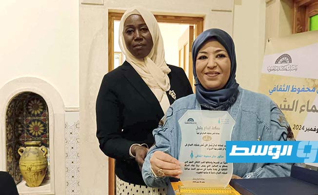 الشاعرة حنان محفوظ مديرة «صالون حنان محفوظ» والشاعرة أم الخير الباروني تقدمان درع التكريم لـ«بيت إسكندر». (بوابة الوسط)